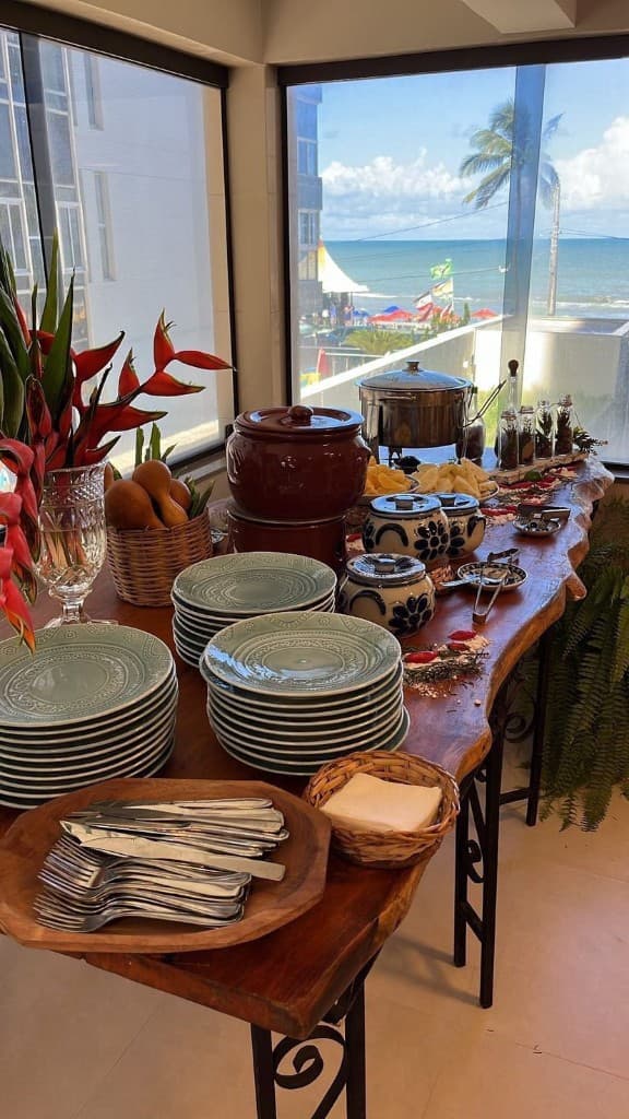 Mesa de feijoada completa com louças e vista para o mar